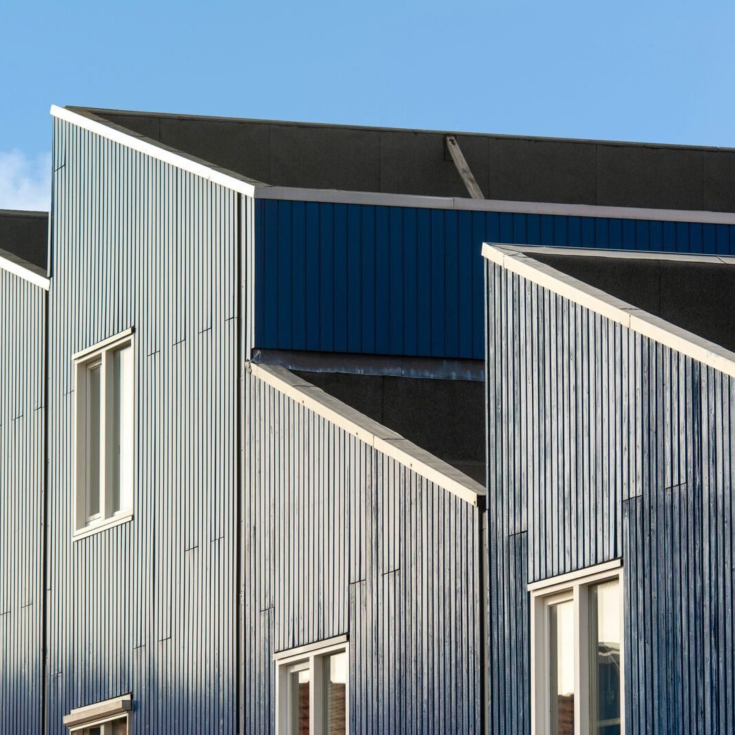 Contemporary geometric building facade with large windows under clear blue sky.