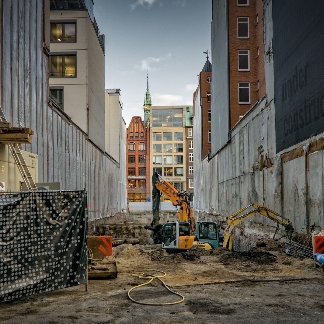 Construction site in an urban area with excavators and scaffolding, showcasing development.