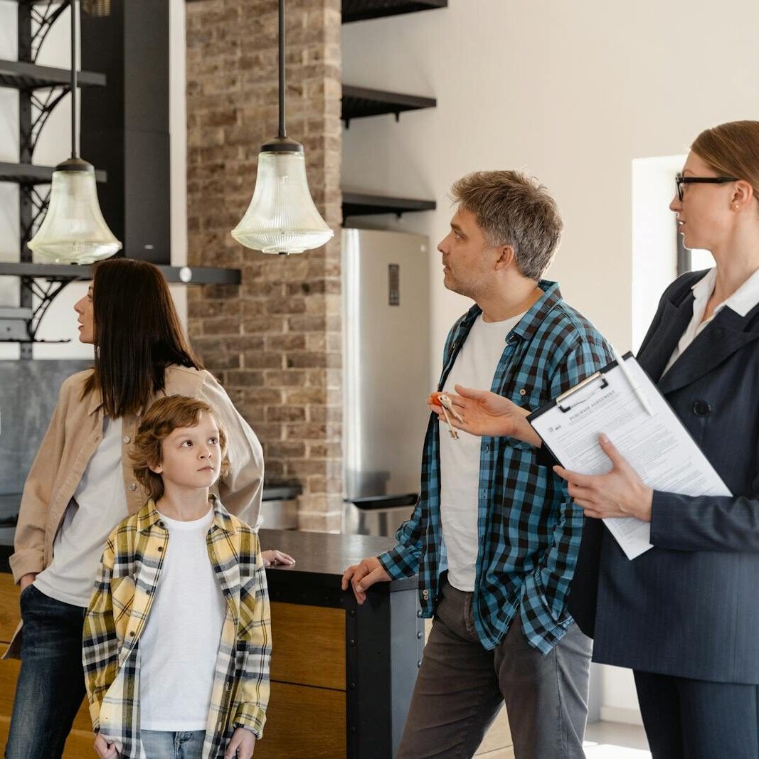 A family converses with a real estate agent about a modern home interior.
